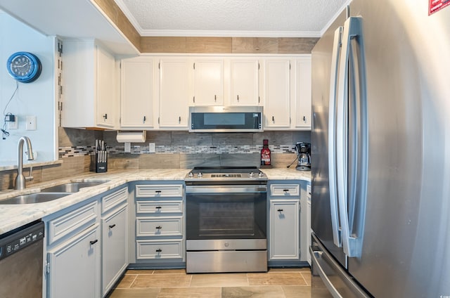 kitchen with sink, white cabinetry, ornamental molding, appliances with stainless steel finishes, and decorative backsplash