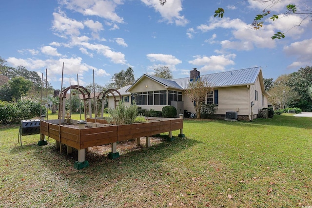 rear view of house featuring a sunroom, a yard, and central AC