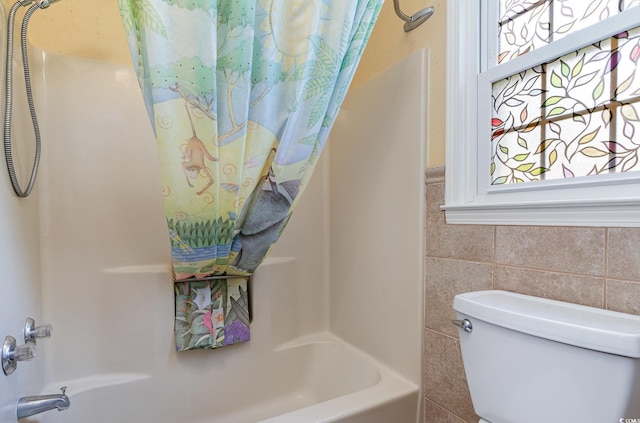 bathroom with shower / bath combo, tile walls, and toilet