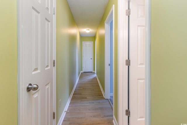 hall with a textured ceiling and light hardwood / wood-style floors