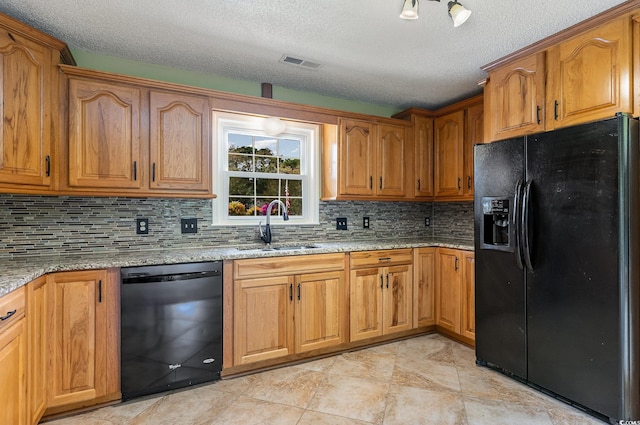 kitchen featuring a textured ceiling, black appliances, sink, and light stone counters