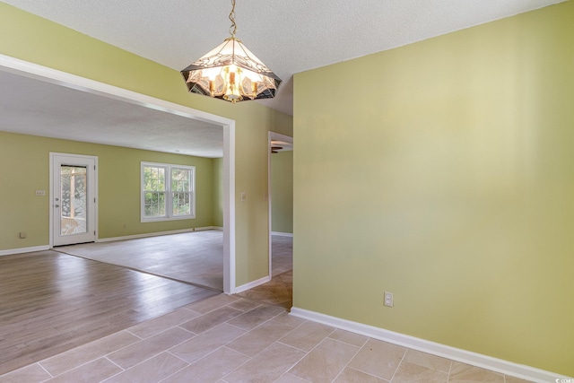 empty room with light wood-type flooring and a textured ceiling