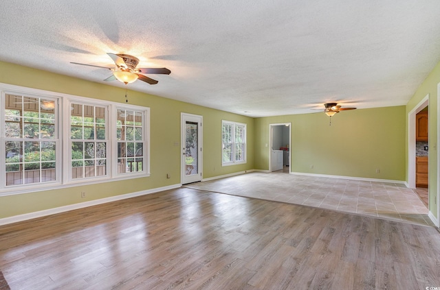 empty room with ceiling fan, a textured ceiling, and light wood-type flooring