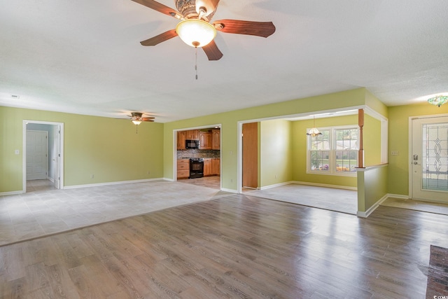 unfurnished living room featuring light wood-type flooring and ceiling fan with notable chandelier