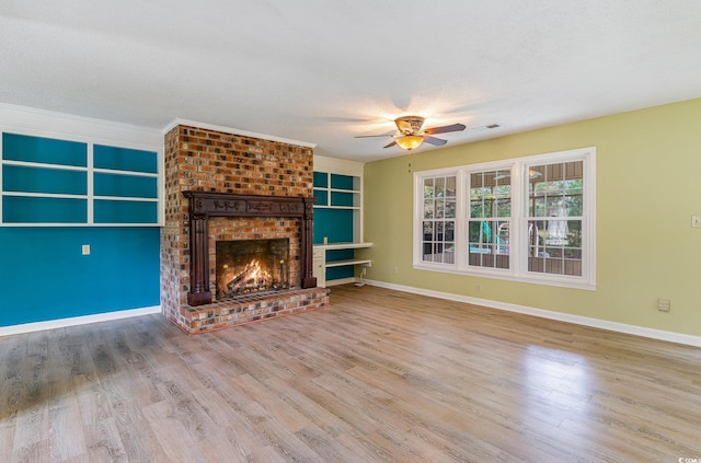 unfurnished living room with light wood-type flooring, a textured ceiling, ornamental molding, and a brick fireplace