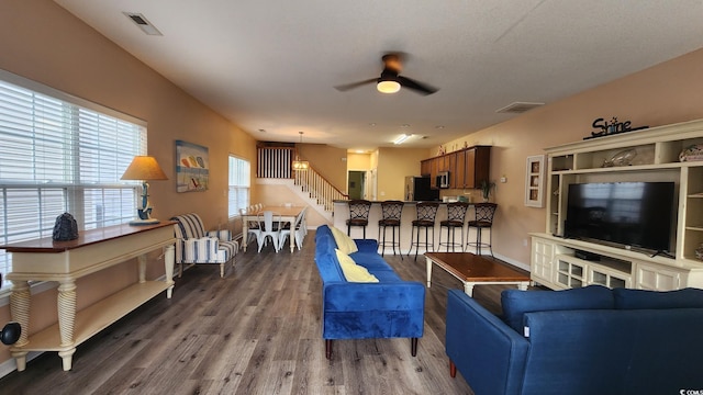 living room featuring dark wood-type flooring and ceiling fan