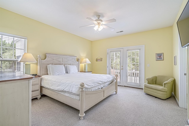 bedroom featuring multiple windows, access to outside, light colored carpet, and french doors