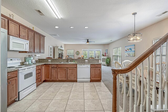 kitchen with sink, white appliances, hanging light fixtures, light tile patterned flooring, and kitchen peninsula