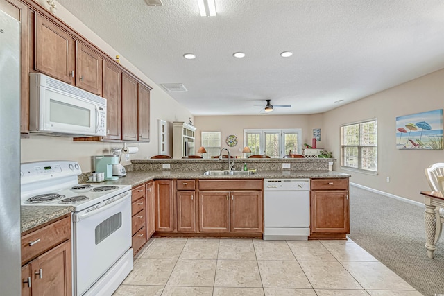 kitchen with light tile patterned flooring, sink, white appliances, and kitchen peninsula