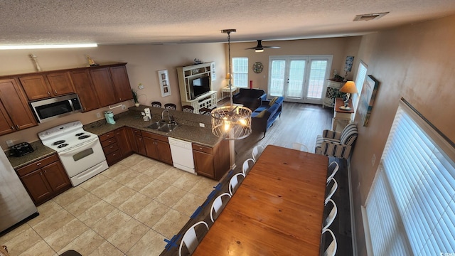 kitchen with sink, white appliances, kitchen peninsula, a textured ceiling, and french doors