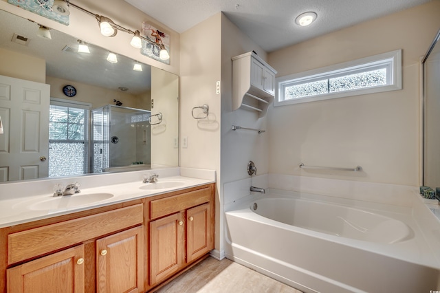 bathroom with vanity, a textured ceiling, and separate shower and tub