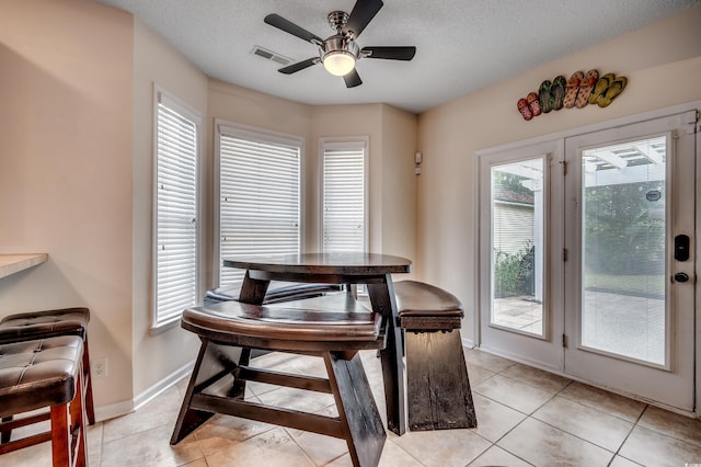 dining room with a textured ceiling, light tile patterned floors, and ceiling fan