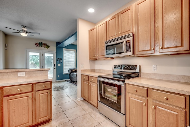 kitchen with a textured ceiling, light tile patterned flooring, ceiling fan, light brown cabinets, and appliances with stainless steel finishes