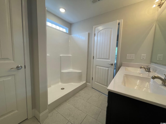 bathroom featuring tile patterned flooring, vanity, and walk in shower