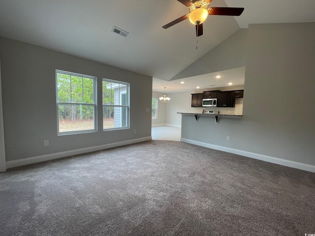 unfurnished living room featuring ceiling fan with notable chandelier, high vaulted ceiling, and carpet floors