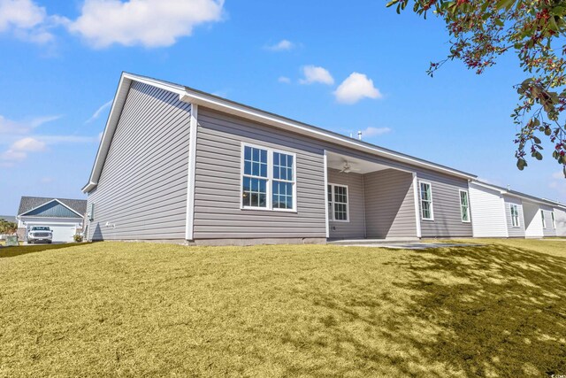 rear view of house featuring ceiling fan, a yard, and a patio area