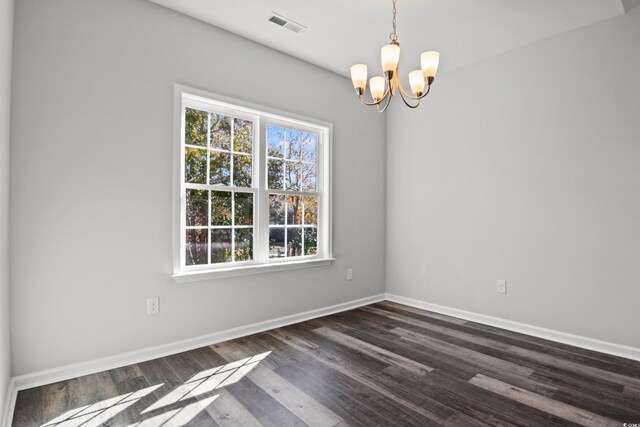 spare room featuring dark hardwood / wood-style flooring and a chandelier