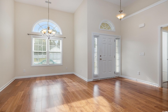 entryway with high vaulted ceiling, light hardwood / wood-style floors, and an inviting chandelier