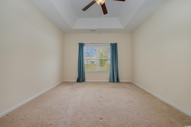 spare room featuring carpet, a tray ceiling, and ceiling fan