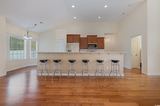 kitchen with a chandelier, wood-type flooring, stainless steel appliances, and high vaulted ceiling