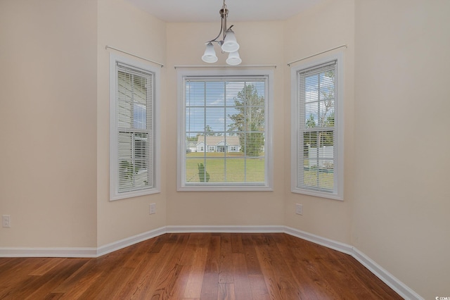 unfurnished dining area with hardwood / wood-style floors and an inviting chandelier