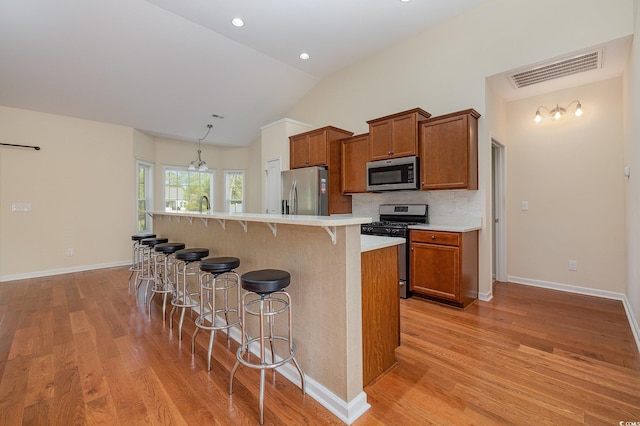 kitchen featuring light wood-type flooring, stainless steel appliances, vaulted ceiling, and a kitchen island