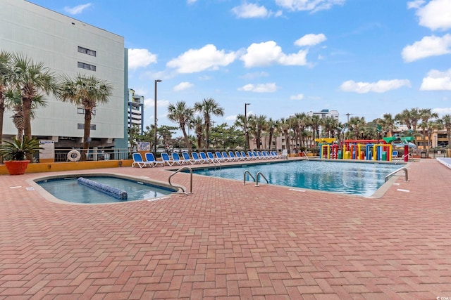 view of swimming pool with pool water feature, a hot tub, and a patio