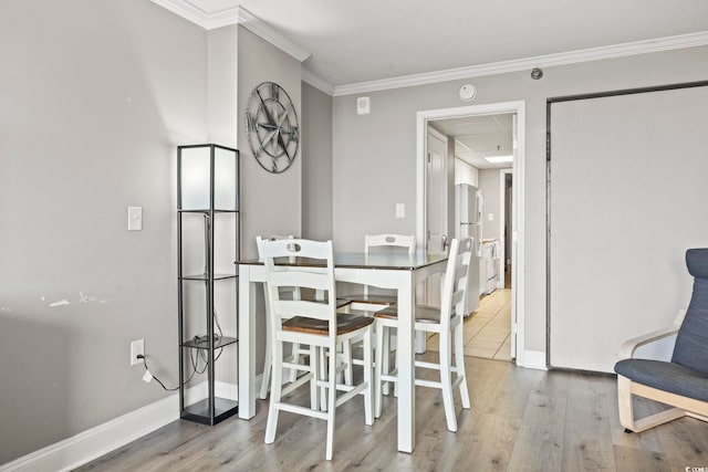 dining space with ornamental molding and light hardwood / wood-style floors