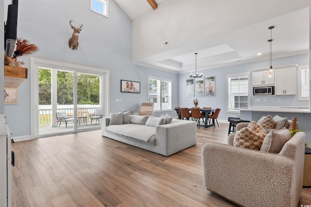 living room with light wood-type flooring, a raised ceiling, baseboards, and visible vents