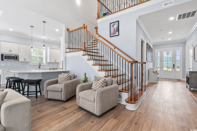 foyer with visible vents, stairway, crown molding, and wood finished floors