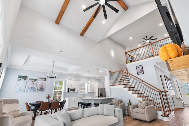 living room with visible vents, stairway, wood finished floors, and ceiling fan with notable chandelier