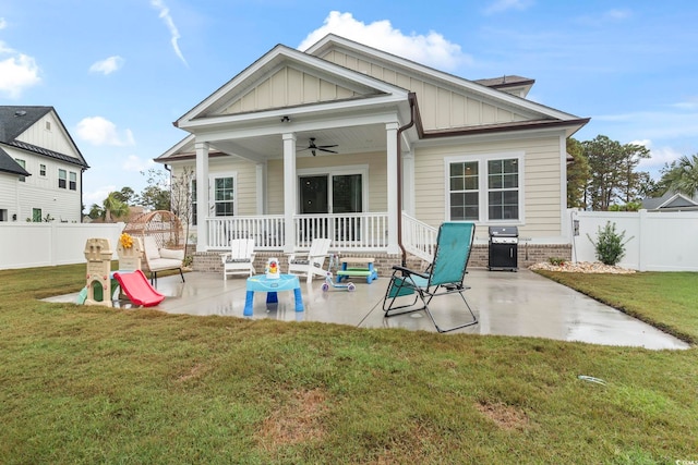 rear view of property featuring a patio, a ceiling fan, board and batten siding, and a lawn