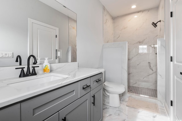 bathroom with vanity, toilet, marble finish floor, and a tile shower