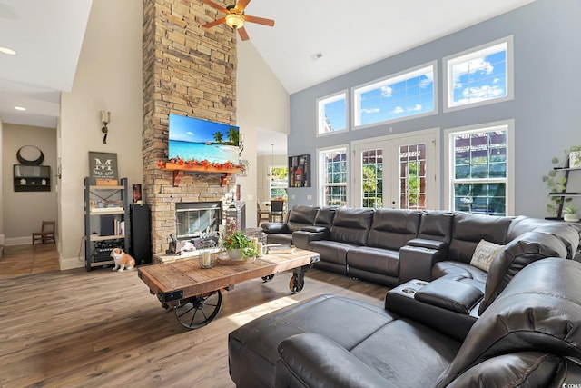 living room featuring french doors, a fireplace, high vaulted ceiling, ceiling fan, and light hardwood / wood-style flooring