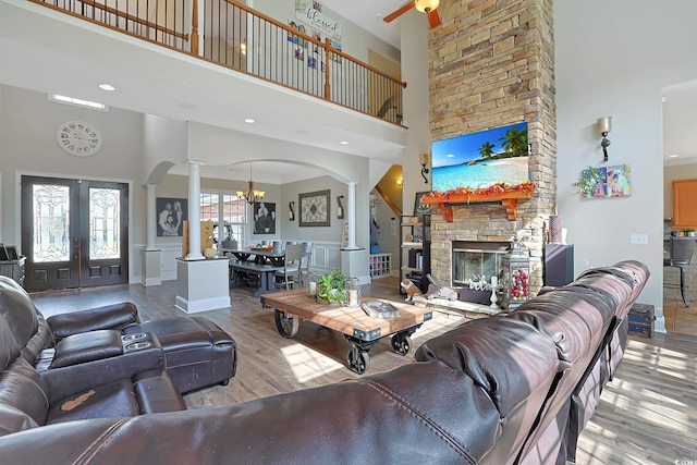 living room featuring ornamental molding, a towering ceiling, light hardwood / wood-style floors, and a fireplace