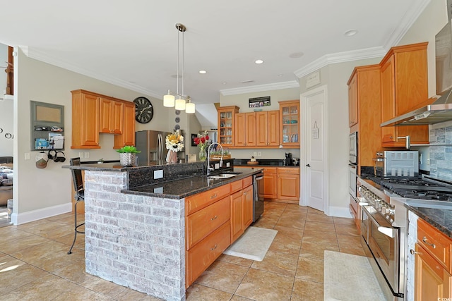 kitchen featuring stainless steel appliances, a center island with sink, sink, dark stone counters, and hanging light fixtures