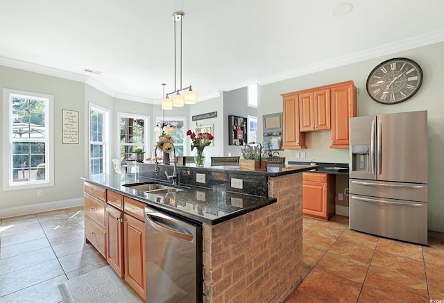 kitchen featuring sink, appliances with stainless steel finishes, dark stone counters, a kitchen island with sink, and crown molding