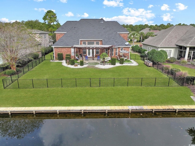 rear view of house with a lawn, a water view, and a patio area