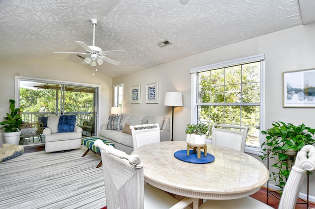 dining room with light wood-type flooring, a healthy amount of sunlight, ceiling fan, and vaulted ceiling