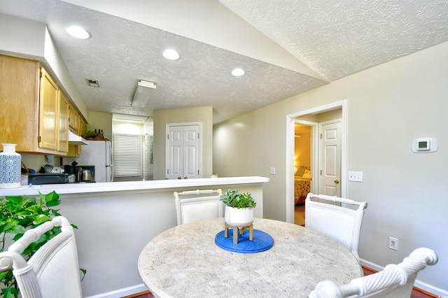 dining area with vaulted ceiling and a textured ceiling