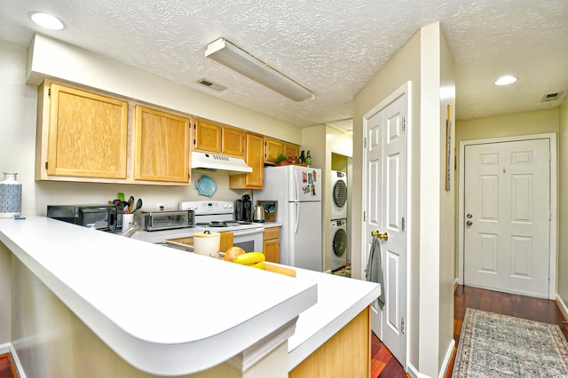 kitchen with white appliances, stacked washer and dryer, kitchen peninsula, and dark hardwood / wood-style flooring