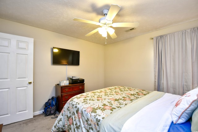 bedroom featuring a textured ceiling, light colored carpet, and ceiling fan