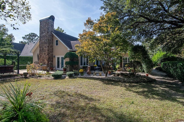 rear view of property with french doors and a lawn