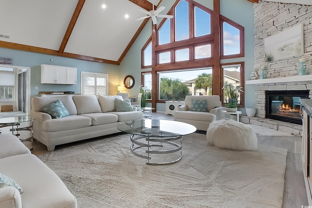 living room featuring hardwood / wood-style flooring, high vaulted ceiling, ceiling fan, beam ceiling, and a fireplace