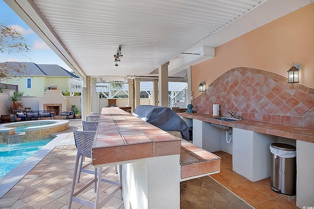 view of patio with area for grilling, sink, and an in ground hot tub