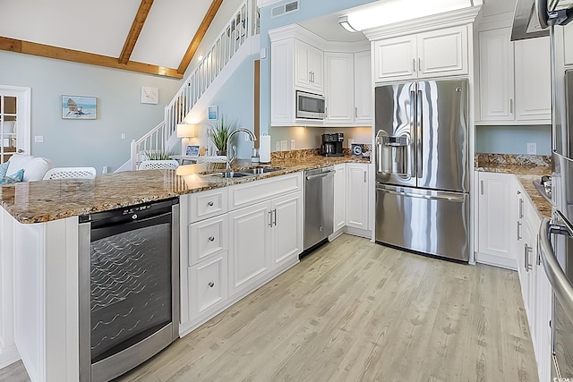 kitchen featuring white cabinets, kitchen peninsula, stainless steel appliances, and beam ceiling