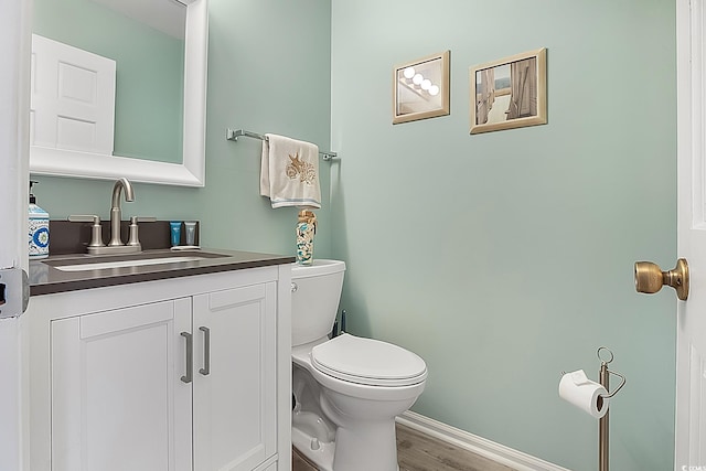 bathroom with toilet, vanity, and wood-type flooring