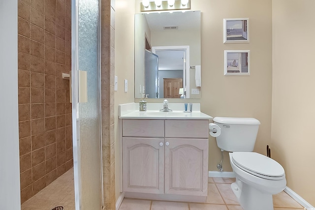 bathroom featuring toilet, tile patterned flooring, vanity, and a tile shower