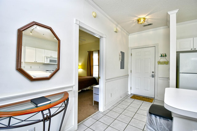 entryway featuring a textured ceiling, light tile patterned floors, and crown molding