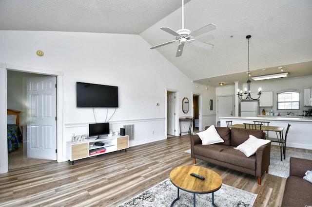 living room featuring ceiling fan with notable chandelier, light wood-type flooring, and high vaulted ceiling